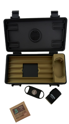Ein geöffneter schwarzer Reise-Humidor mit hellbeigen Innenfächern zur Zigarrenaufbewahrung. Unter dem Humidor liegen ein braunes Boveda Feuchtigkeitspad mit 72% Aufschrift, ein schwarzer Zigarrenschneider und ein schwarzes Macardo Zigarren-Accessoire.